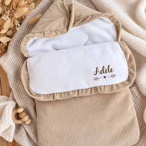 Nid d'ange bébé en velours côtelé beige nervuré, doublure polaire blanche et prénom personnalisé écrit en grand sur le rabat — henrietteandco